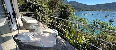 A balcony with wicker furniture and a view of the sea.