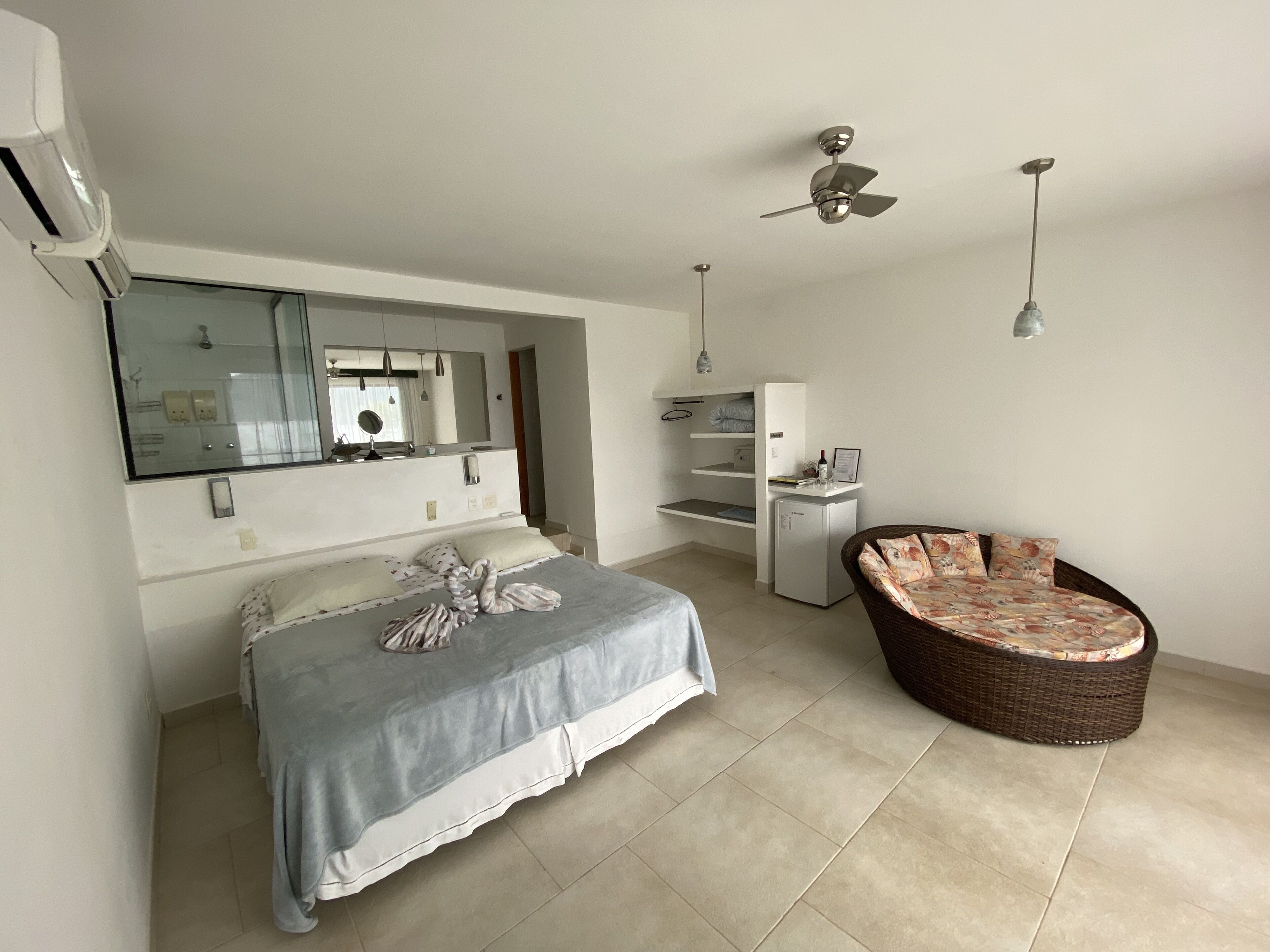Une chambre à coucher moderne, équipée d’un lit, d’un petit bureau, d’une chaise, d’un ventilateur de plafond et d’une armoire intégrée.