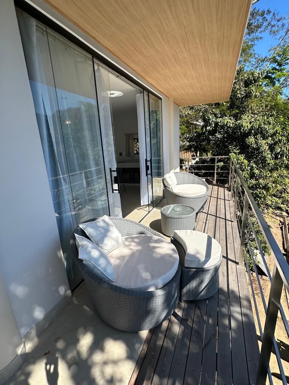 A deck with wicker furniture and a sliding glass door leading to an interior space.