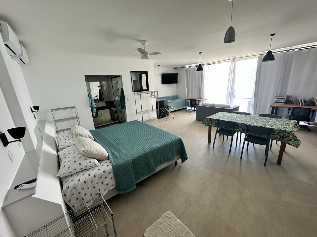 A modern bedroom with a bed, bedside table, and a desk area with a chair.