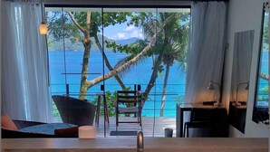 A bathroom with a large sink, a ceiling fan, and a view of the ocean through large windows. - Asalem (Angra dos Reis)