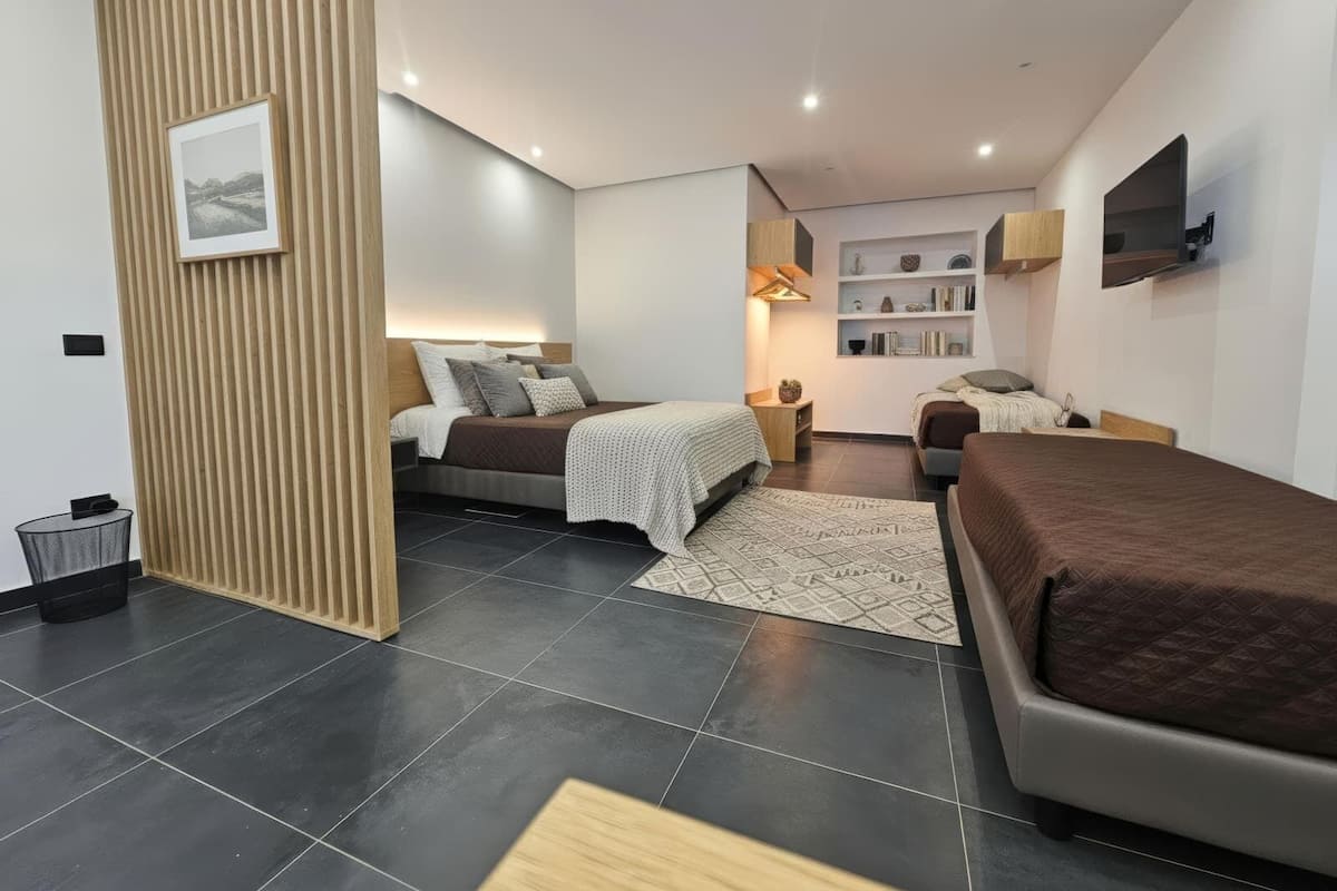 Een moderne slaapkamer met twee bedden, een klein bureau en een aan de muur bevestigde televisie.