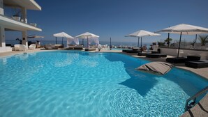 A swimming pool with lounge chairs and umbrellas, a clear sky, and a view of the sea. - Hotel Sporting Club (Altavilla Milicia)