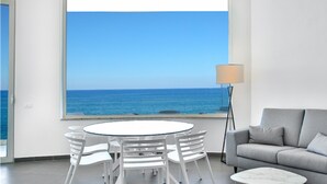 A room with a view of the sea, a round table with chairs, a grey sofa, and a floor lamp. - Hotel Sporting Club (Altavilla Milicia)