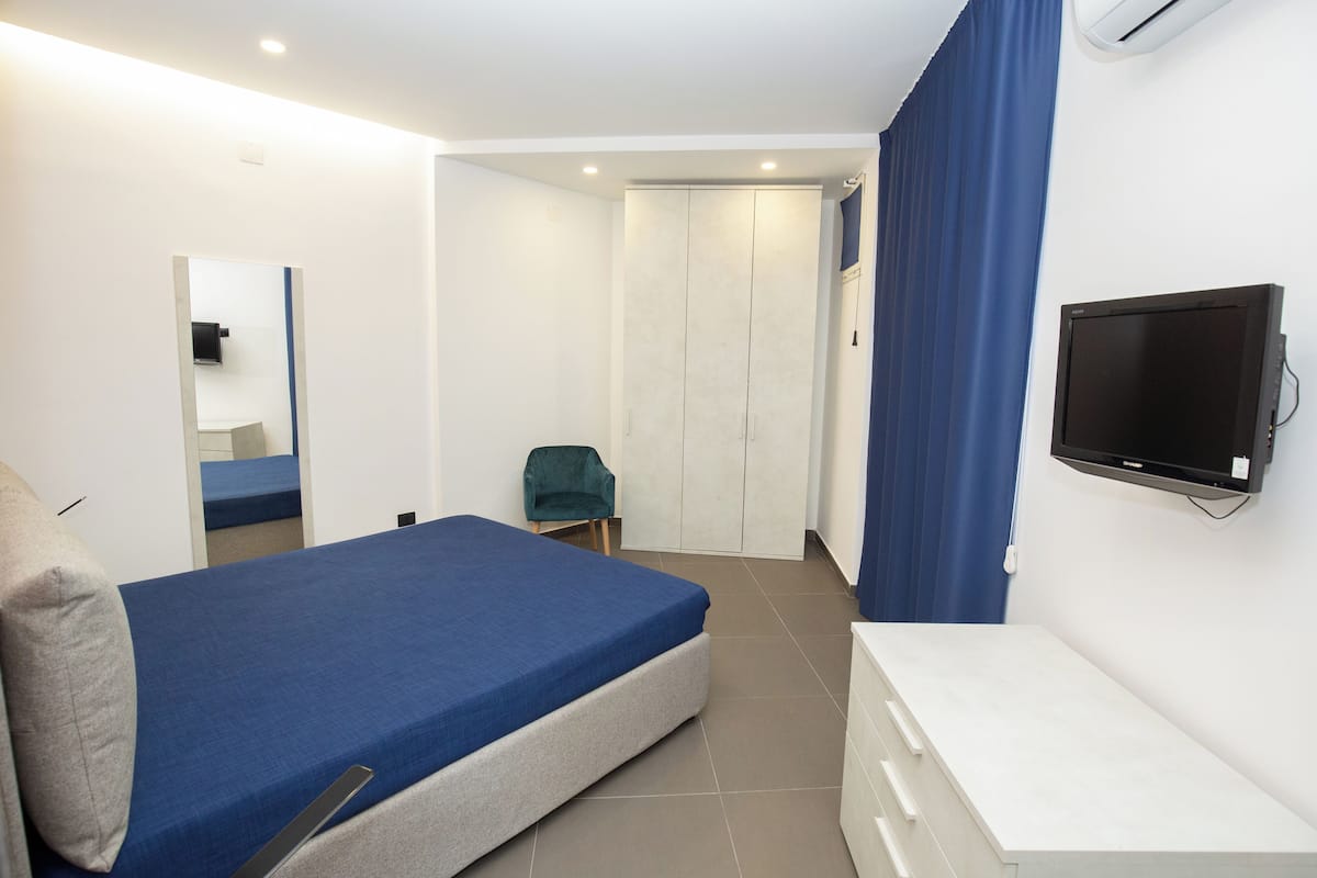 Een slaapkamer met een bed, een televisie, een kledingkast en een stoel.