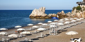 A beach with white umbrellas and sun loungers, rocky cliffs, and a clear blue sea. - Hotel Sporting Club (Altavilla Milicia)