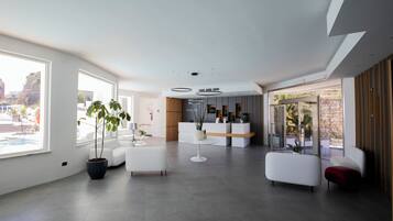 Un intérieur moderne comprenant un comptoir d’accueil, un espace salon et de grandes fenêtres offrant une vue sur l’extérieur.