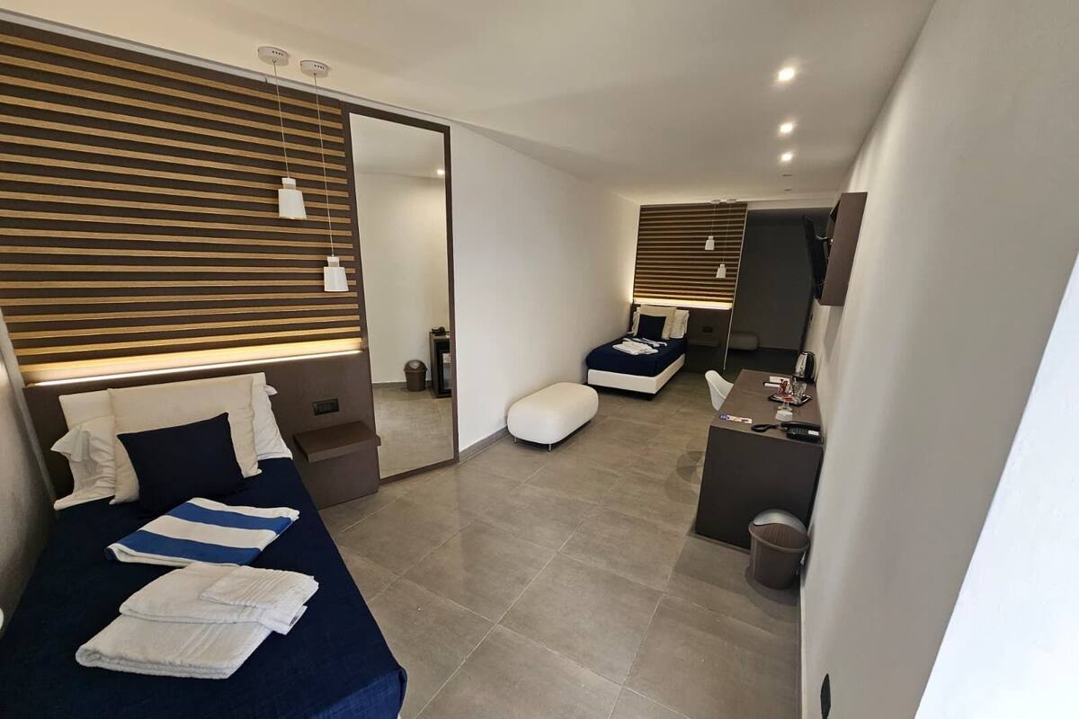 Een moderne hotelkamer met een groot bed, een bureau, een zithoek en een spiegel.