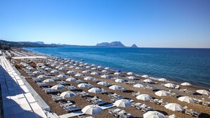 A beach with rows of sunbeds and umbrellas, a clear blue sky, and distant mountains. - Hotel Sporting Club (Altavilla Milicia)