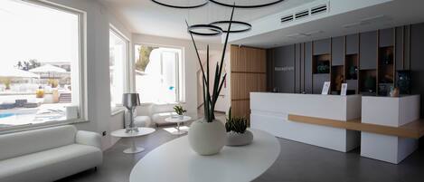Ein moderner Empfangsbereich mit einer weißen Rezeption, einem runden Tisch mit einer Vase und einer Couch.