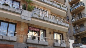 Un edificio de varios pisos con balcones, una cafetería llamada "Alogar" y una tienda llamada "Cacau Sampa".