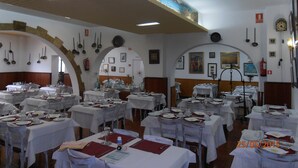 A dining area with multiple tables set for service, a clock on the wall, and a mural overhead. - Hotel Marblau Tossa (Tossa de Mar)
