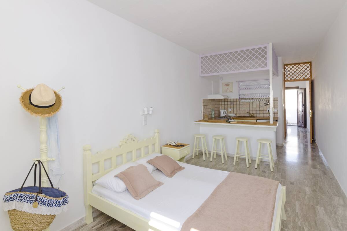 A bedroom with a bed, a nightstand, a hat, and a woven basket.