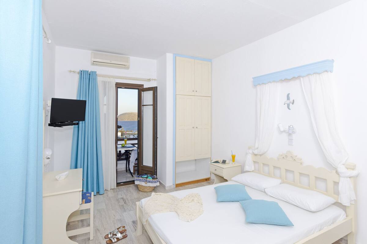 A bedroom with a bed, a TV, a desk, and a wardrobe.