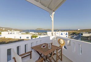 A terrace with a table and chairs, overlooking a coastal village with white buildings and the sea. - Castillio Hotel (Astypalaia)