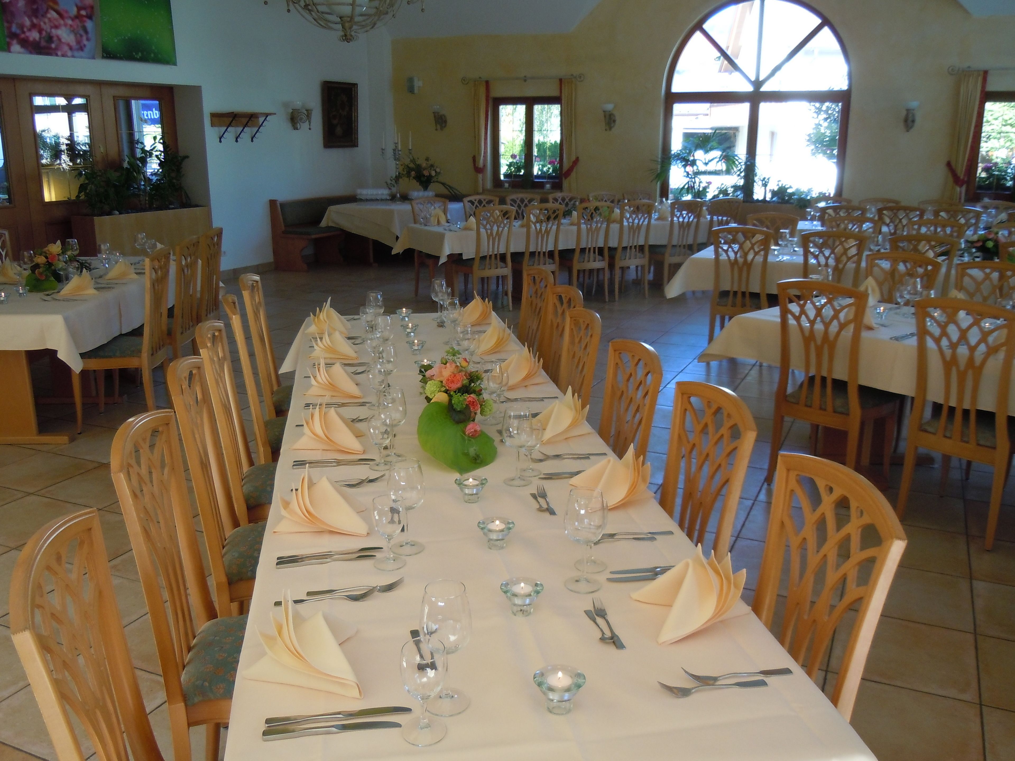 Una larga mesa de comedor dispuesta con sillas, un florero de flores y velas.