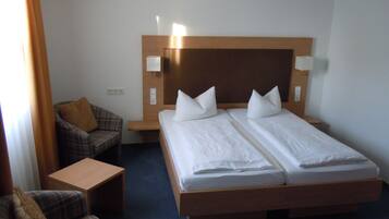 A hotel room with a double bed, two bedside tables, a chair, and a small table.