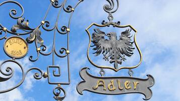 Un letrero de metal con un escudo y el nombre "Adler" sobre un cielo azul despejado.