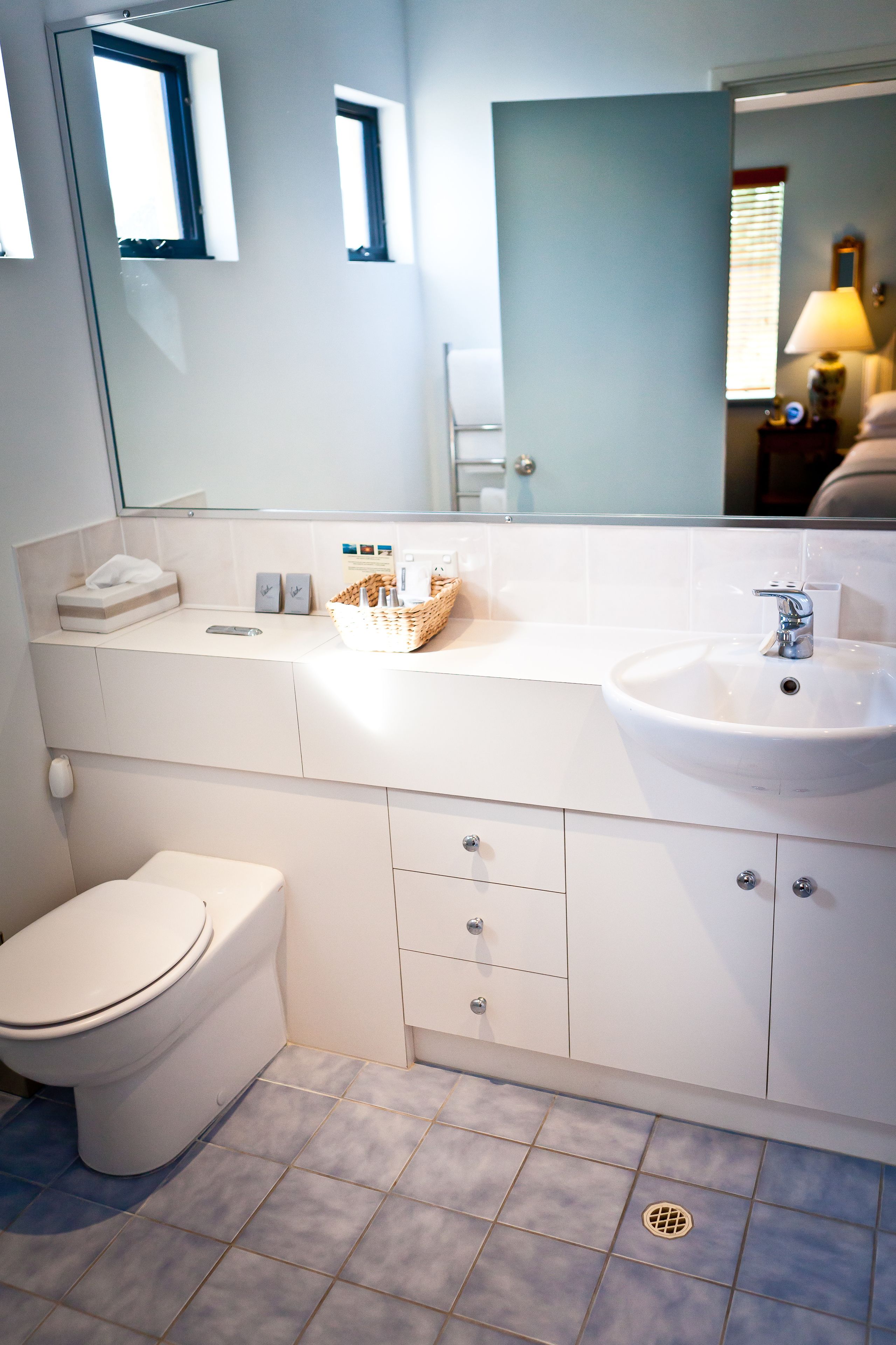Een moderne badkamer met een wit toilet, een wastafel en een spiegel.