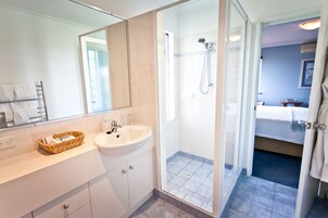 Un baño moderno con ducha de vidrio, lavamanos y espejo.