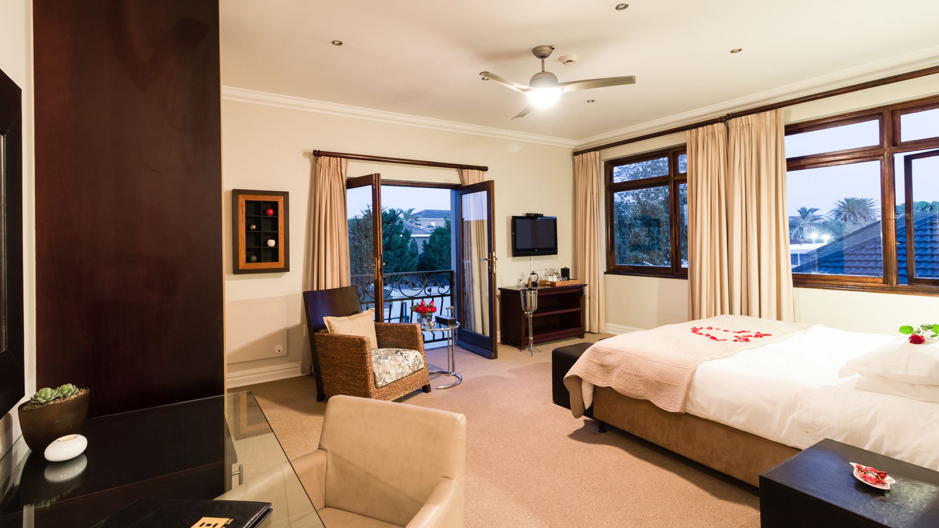 Una habitación de hotel con cama, escritorio, silla, un pequeño balcón y televisión.