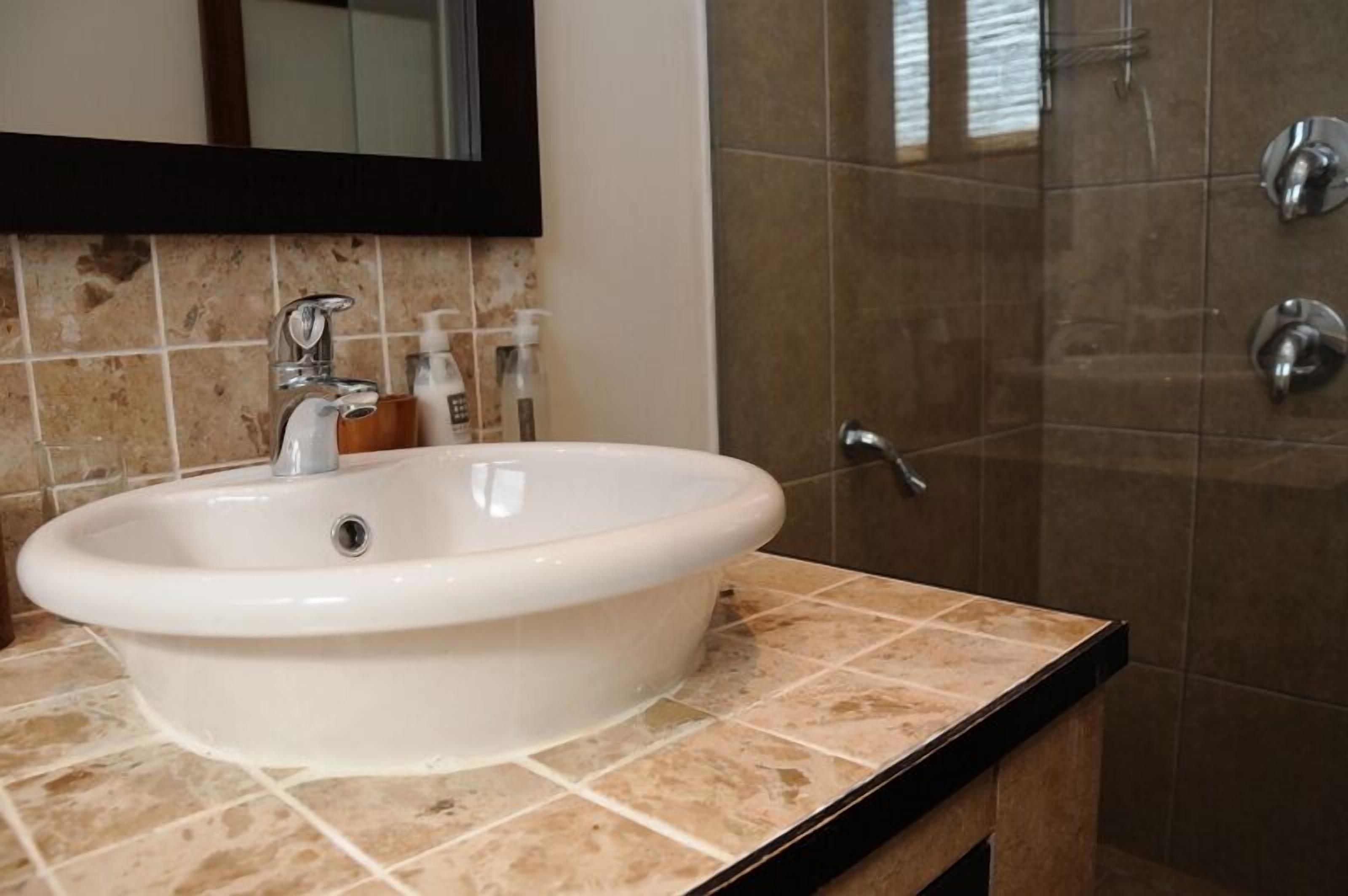 A bathroom with a white sink, a mirror, and a shower area.