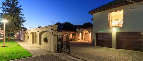 A residential area with a gated entrance, paved walkways, and houses with distinct architectural styles.