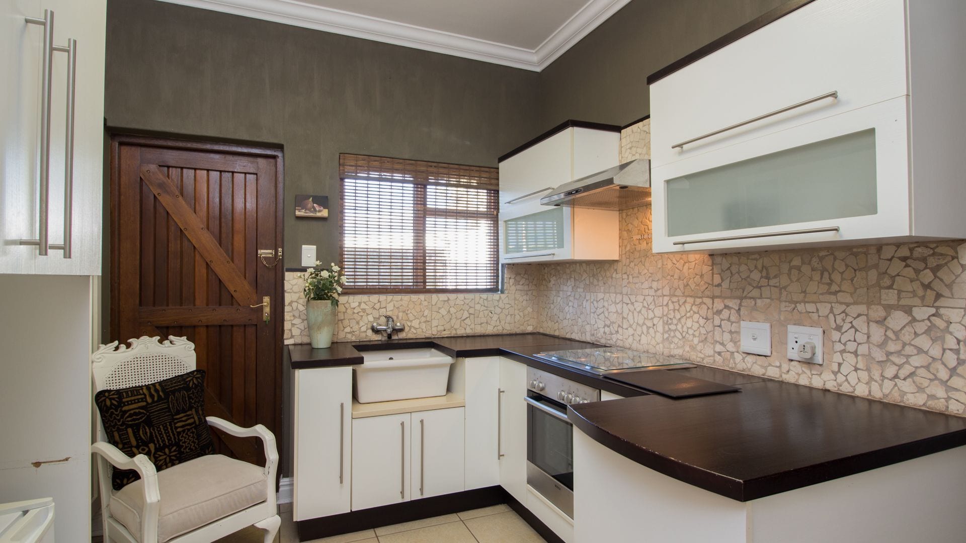 A compact kitchen with white cabinets, a stone backsplash, and a built-in oven.