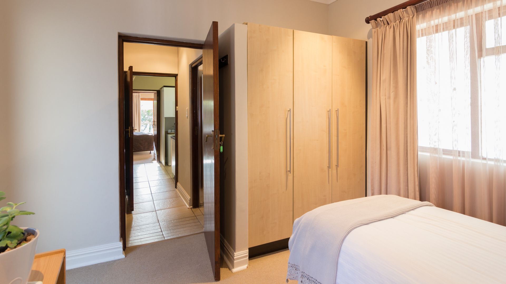 A bedroom with a bed, a wardrobe, and a bathroom visible through an open door.