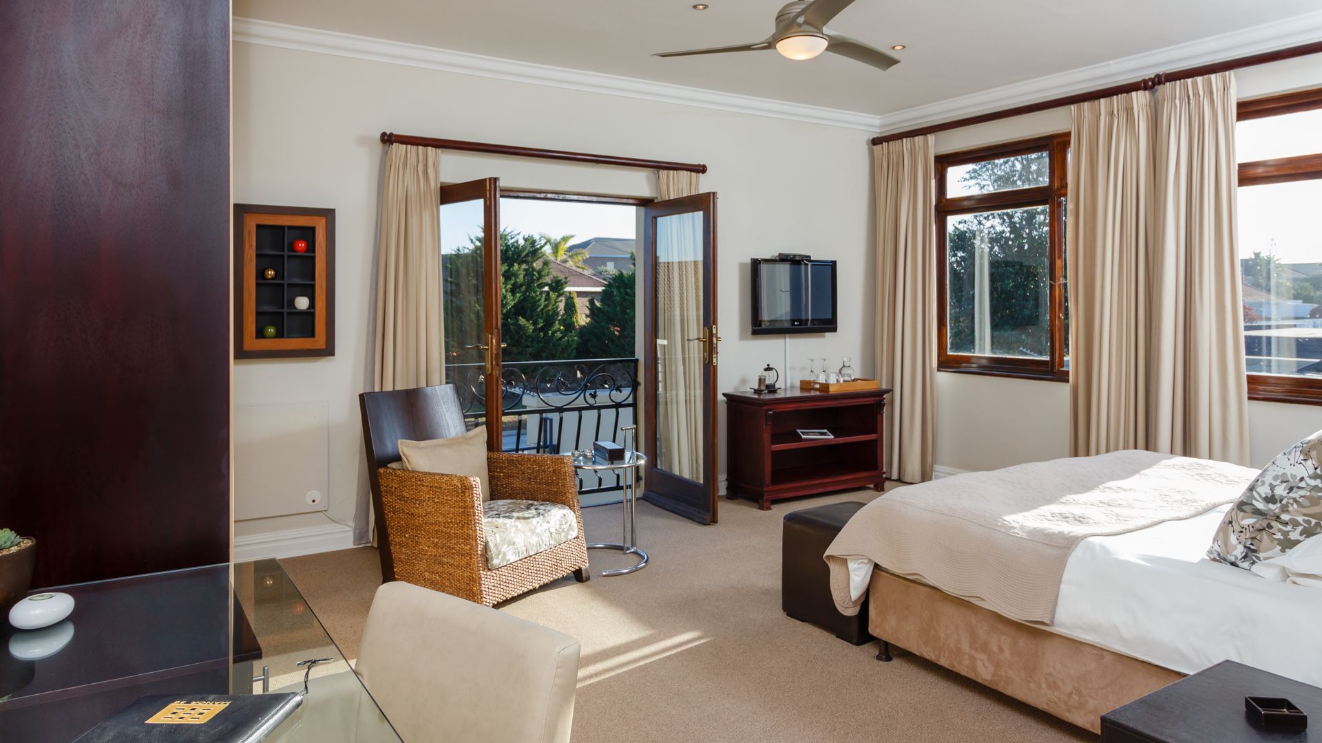 Habitación de hotel con cama, una silla, un escritorio, televisor y balcón con vistas.