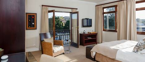 A hotel room with a bed, a chair, a desk, a TV, and a balcony with a view.