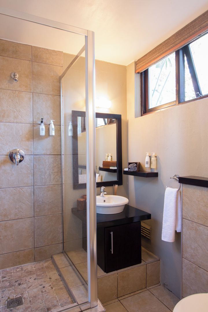 Une salle de bain moderne avec une douche à parois de verre, un meuble-lavabo noir, un lavabo blanc et un grand miroir.