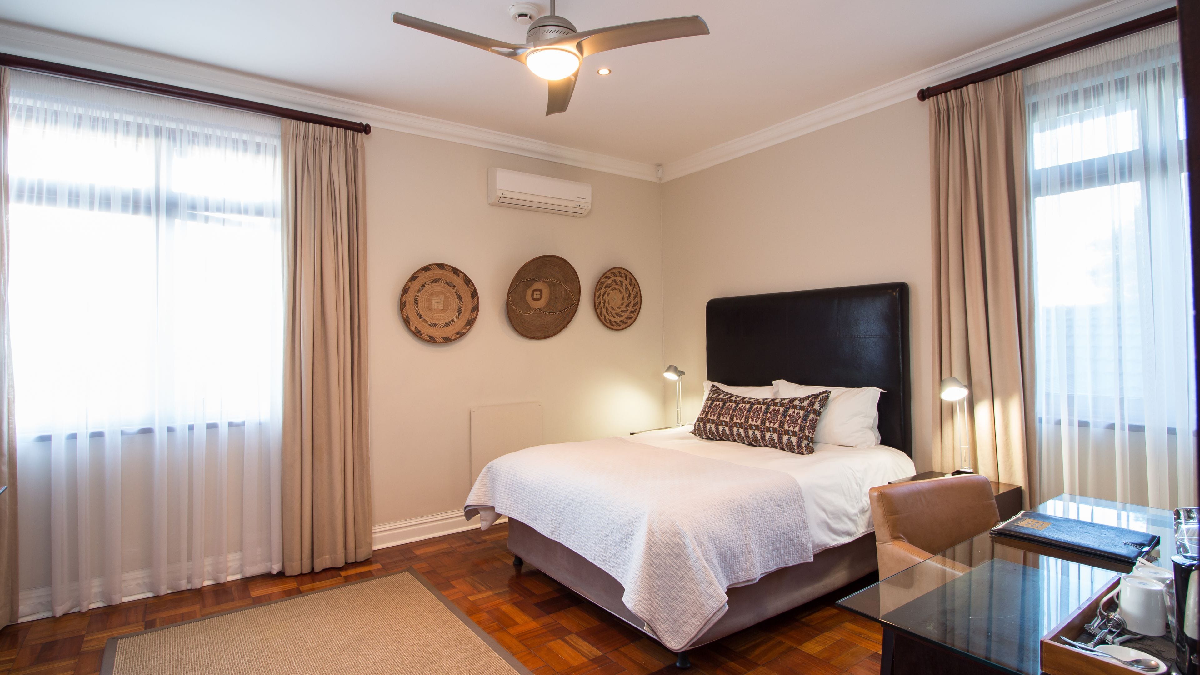 A well-lit bedroom with a bed, a ceiling fan, and a bedside table with a lamp.