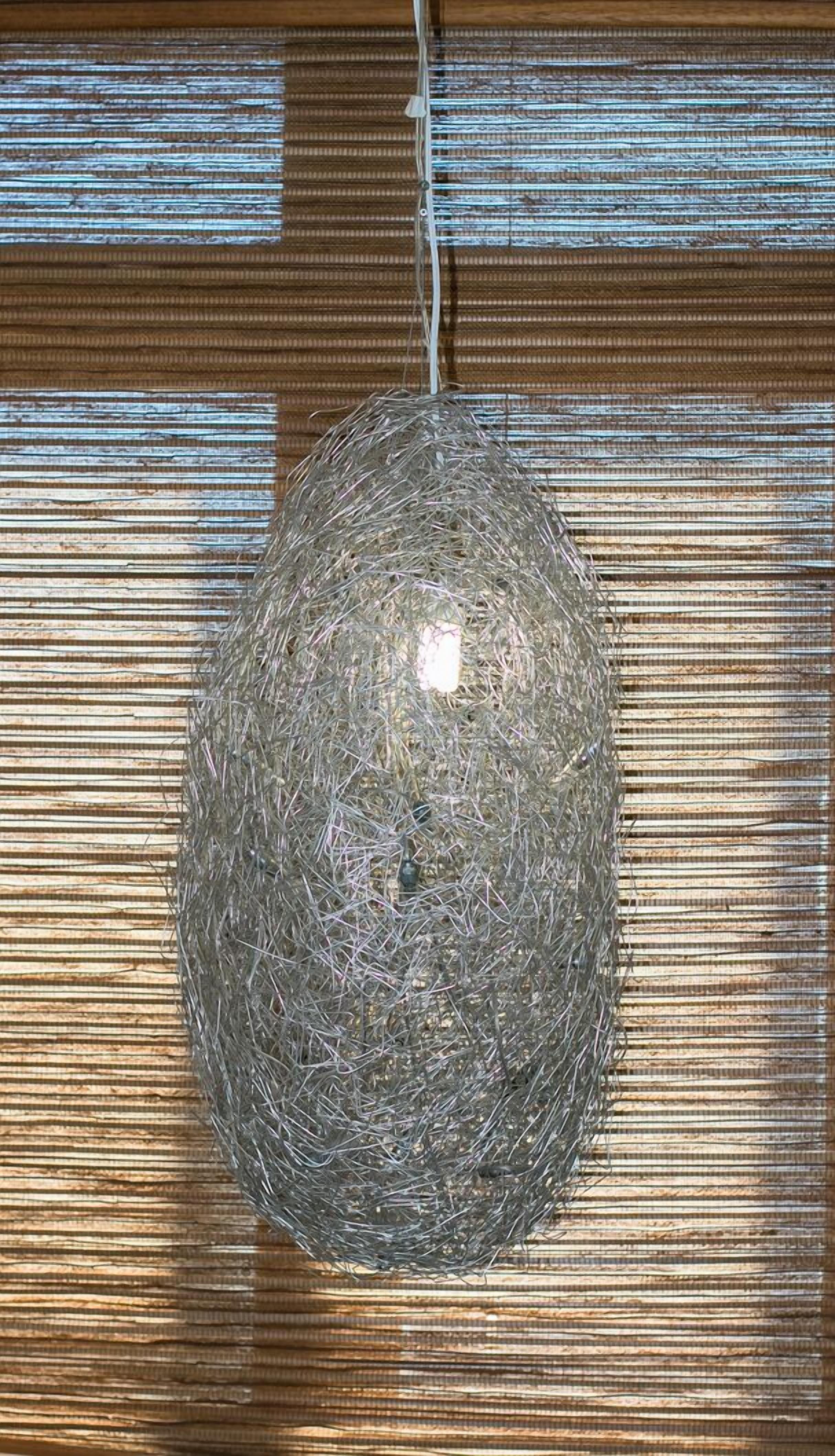 A hanging light fixture made of intertwined metal wires.