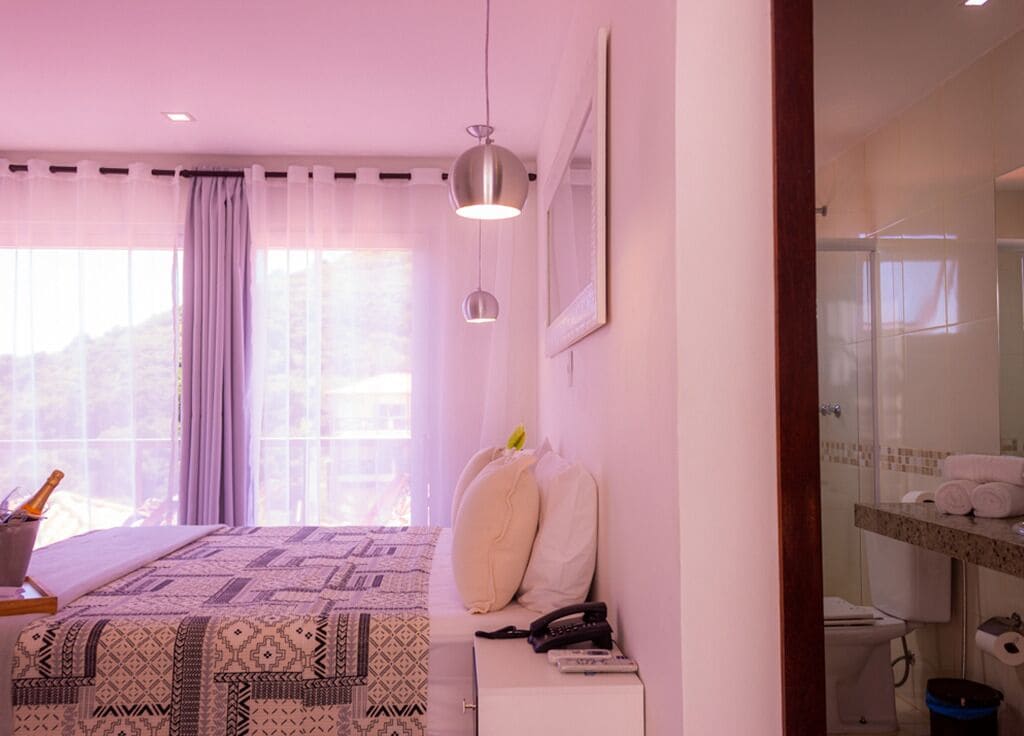 A bedroom with a bed, bedside table, and a view of the outside.