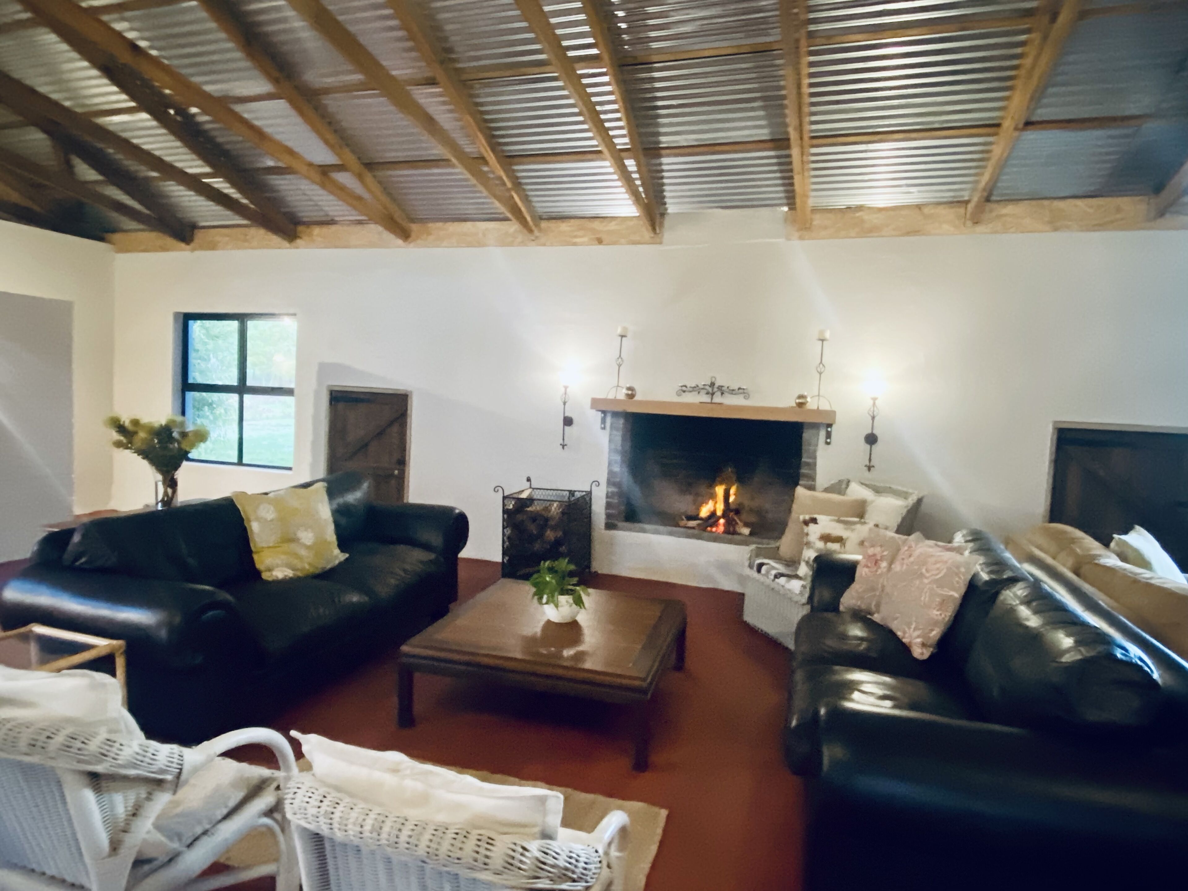 Un accogliente soggiorno con camino, divani in pelle e soffitto in legno.