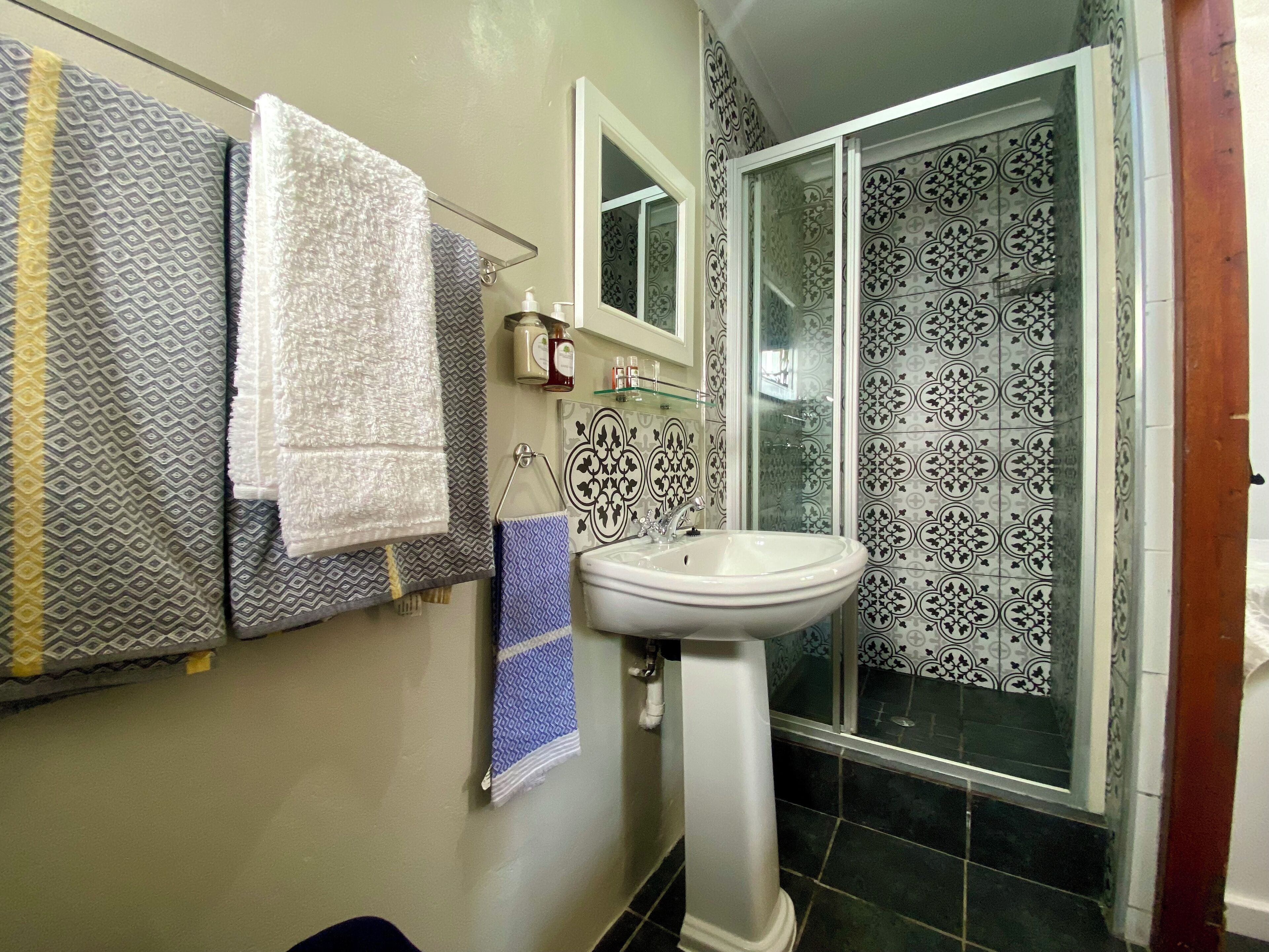 A bathroom with patterned tiles, a sink, and a glass shower enclosure.