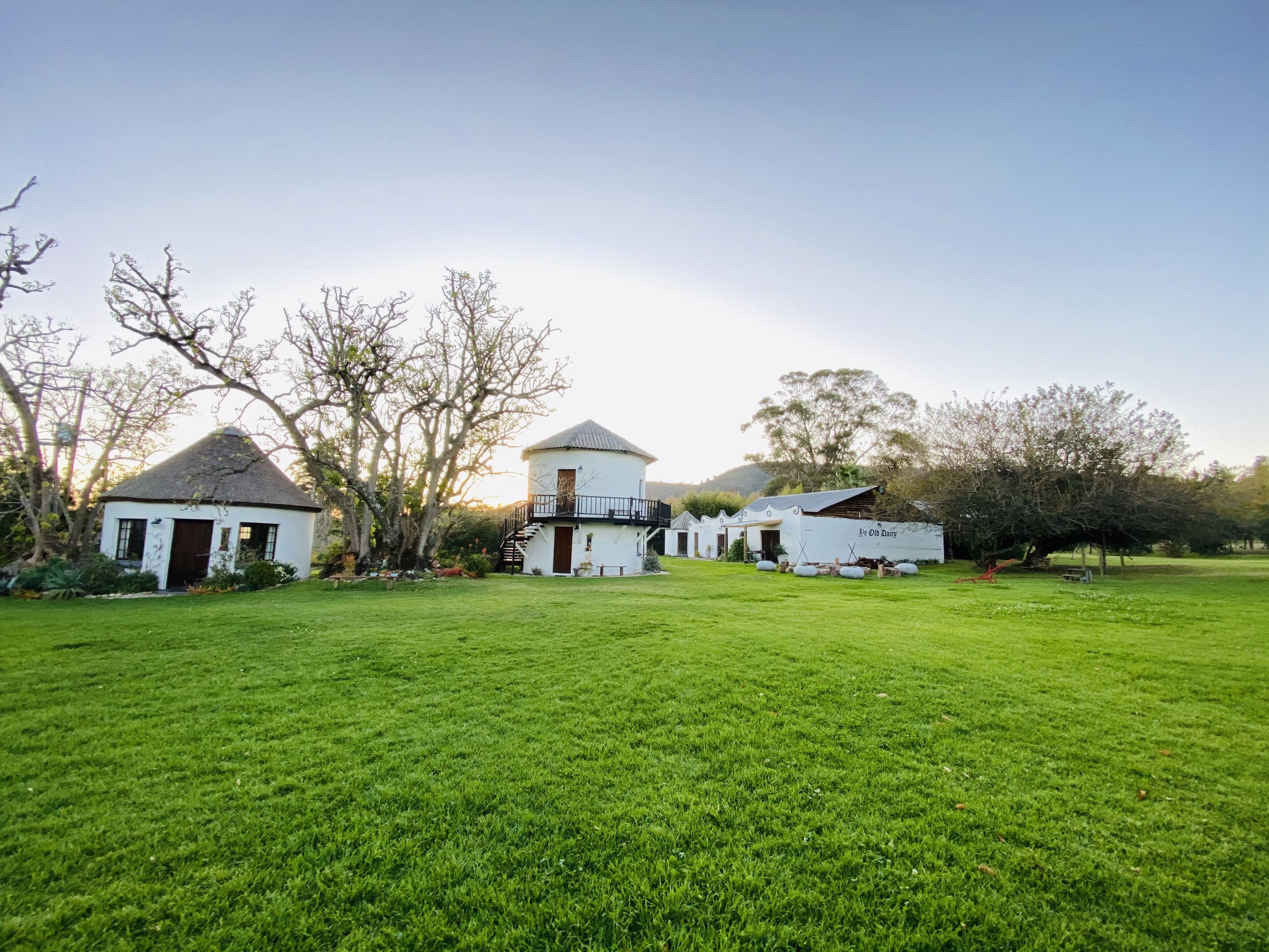 A rural property with a large grassy field, a white house with a thatched roof, and a barn labeled "Old Dairy."