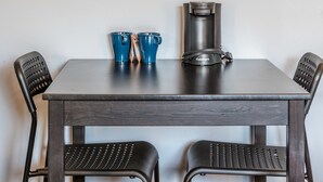 Un coin repas comprenant une table, deux chaises, une machine à café et un tableau représentant la Tour Eiffel.