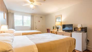 Habitación de hotel con dos camas, ventilador de techo, televisión, microondas y escritorio con lámpara.