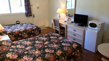 Een kamer met twee bedden, een bureau, een stoel, een televisie, een magnetron en een raam met gordijnen.