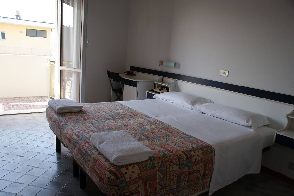 Une chambre d’hôtel avec un lit, un bureau et une chaise.