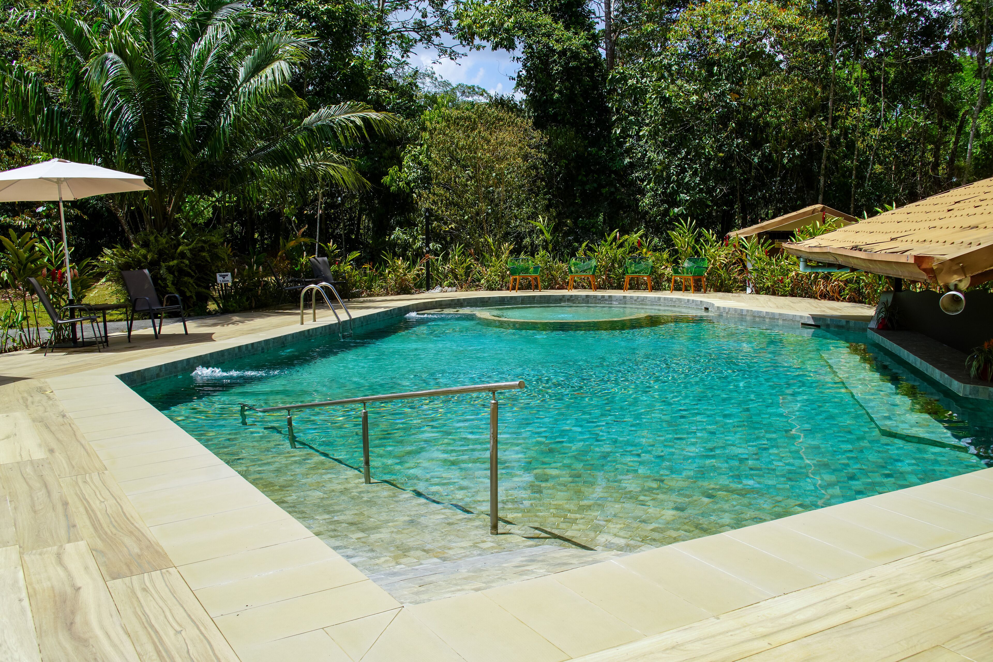 Una piscina cristalina con muelle de madera y sillas de descanso.