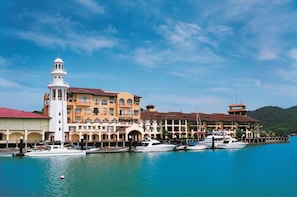 A waterfront hotel with multiple balconies, a lighthouse, and several boats docked. - Resorts World Langkawi (Langkawi)