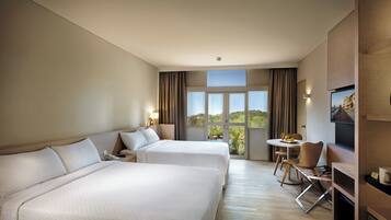 A hotel room with two beds, a dining table with chairs, a television, and a view of the outdoors.