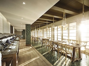 A spacious dining area with long tables and chairs, large windows allowing natural light, and a central pillar with a unique mosaic design. - Resorts World Langkawi (Langkawi)