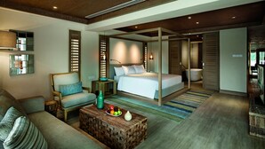 A modern bedroom with a large bed, a sitting area with a sofa and armchair, a wooden coffee table with fruit, and a bathroom with a bathtub. - Resorts World Langkawi (Langkawi)
