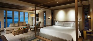 A hotel room with a large bed, a sofa, a chair, a small table with fruit, and a view of the sea through large windows. - Resorts World Langkawi (Langkawi)