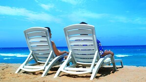 Two white lounge chairs facing the ocean with a clear sky. - Resorts World Langkawi (Langkawi)