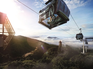 A cable car with passengers, a pagoda, and a mountain landscape with clouds below. - Resorts World Genting - Genting Grand (Genting Highlands)